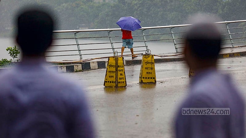 হাতিরঝিল এলাকায় রোববার দুপুরে বৃষ্টির মধ্যে ছাতা হাতে গন্তব্যের পথে অনেকে