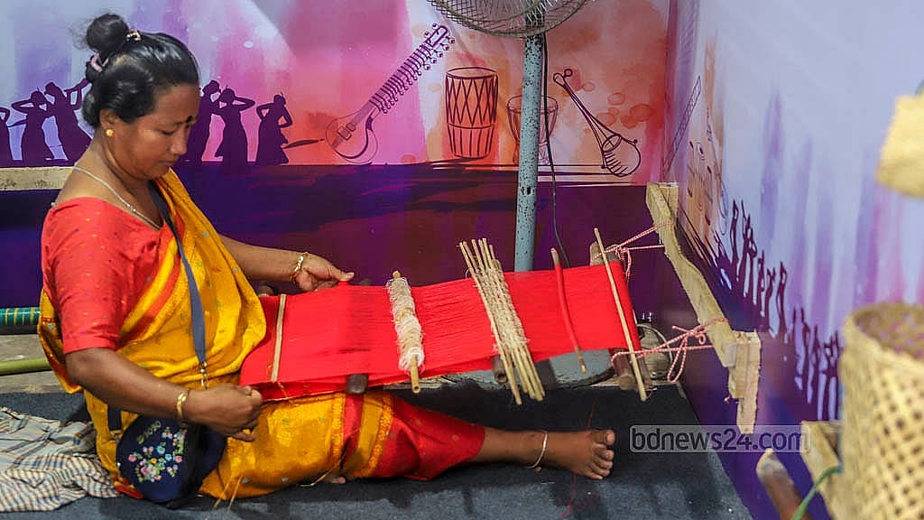 বাংলা একাডেমি প্রাঙ্গণে ‘সকল জাতিগোষ্ঠীর সাংস্কৃতিক ঐতিহ্যের প্রদর্শনীতে’ খাগড়াছড়ির স্টলে তাঁতে কাপড় বুনছেন চাকমা নারী