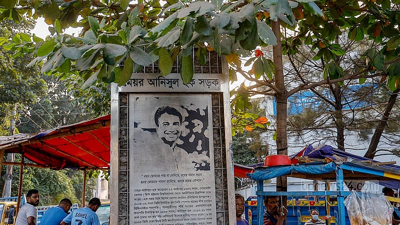 সাত রাস্তা হয়ে মেয়র আনিসুল হক সড়কে প্রবেশের মুখেই নাম ফলক। তার পেছনেই সড়ক দখল করে রাখা হয়েছে ট্রাক