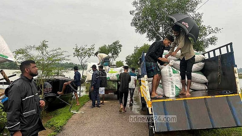 বন্যার কারণে বাড়িঘর প্লাবিত হওয়ায় গোলা থেকে ধান সরিয়ে নিরাপদ আশ্রয়ে নিচ্ছেন সিলেটের পানিবন্দি মানুষজন।