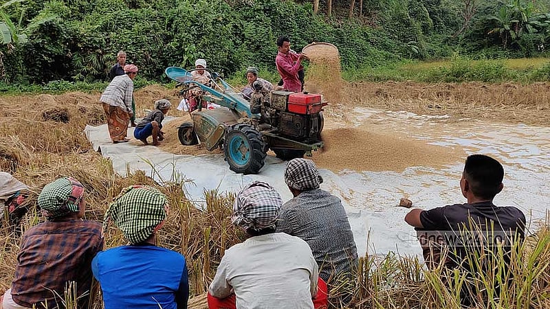 ক্যাপশন- মাড়াই শেষে ট্রাক্টরে পাখা লাগিয়ে ধান পরিষ্কার করে নেওয়া হচ্ছে। কাজ করছেন ‘শ্রম বিনিময়’ প্রথায় বিনা পারিশ্রমিকে শ্রম দিতে আসা লোকজন।