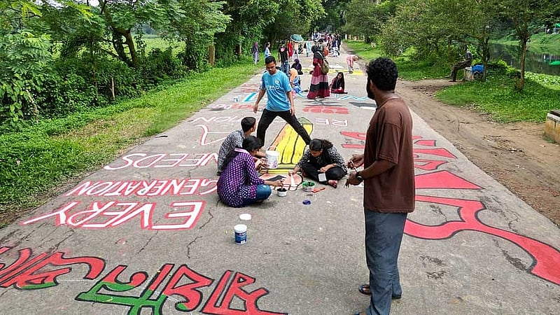 জাহাঙ্গীরনগর বিশ্ববিদ্যালয়ের সড়কে লেখা হচ্ছে প্রতিবাদী স্লোগান