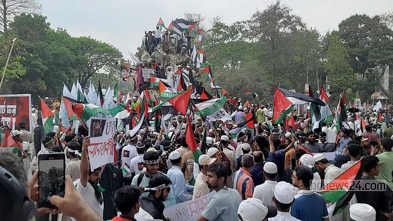 ‘মার্চ ফর গাজা’ কর্মসূচিতে অংশ নিতে আসা অনেকে ফিলিস্তিনের পতাকা হাতে উঠে পড়েন সোহরাওয়ার্দী উদ্যান সংলগ্ন ঢাকা বিশ্ববিদ্যালয়ের রাজু ভাস্কর্যেওর ওপরে। 