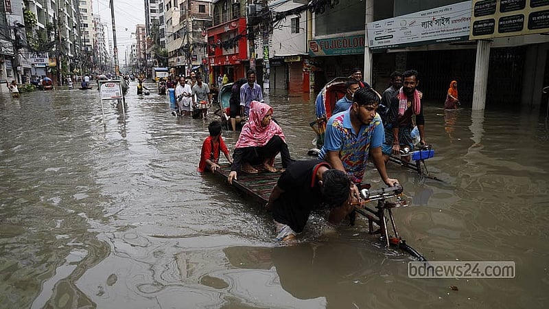ভারি বৃষ্টিতে শুক্রবার রাজধানীর গ্রিন রোডে কোমর সমান পানি জমে গেলে রিকশা-ভ্যানে করে পাড়ি দিতে দেখা যায় অনেককে। ছবি: মাহমুদ জামান অভি
