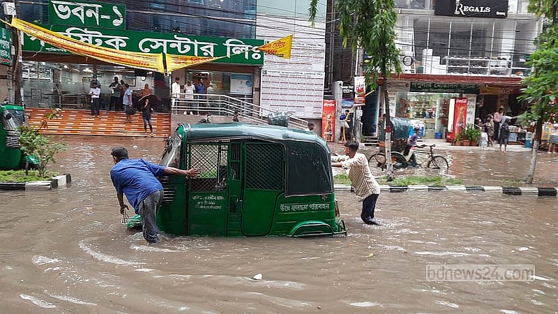 জমে যাওয়া বৃষ্টির পানিতে নষ্ট অটোরিকশা নিয়ে বিপাকে চালক। শুক্রবার সকালে রাজধানীর শান্তিনগরের চিত্র।  ছবি: সুমন মাহমুদ