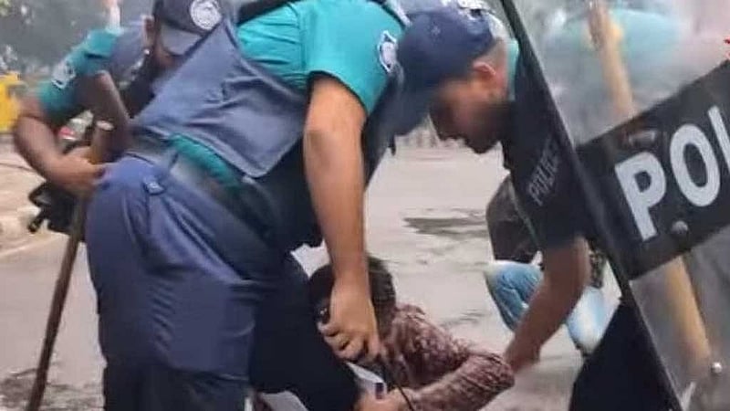 পুলিশ সদস্যের পা চেপে ধরা শিক্ষককে ছাড়িয়ে দিতে বাহিনীর অন্য সদস্যদেরকে আপ্রাণ চেষ্টা করতে দেখা গেছে।