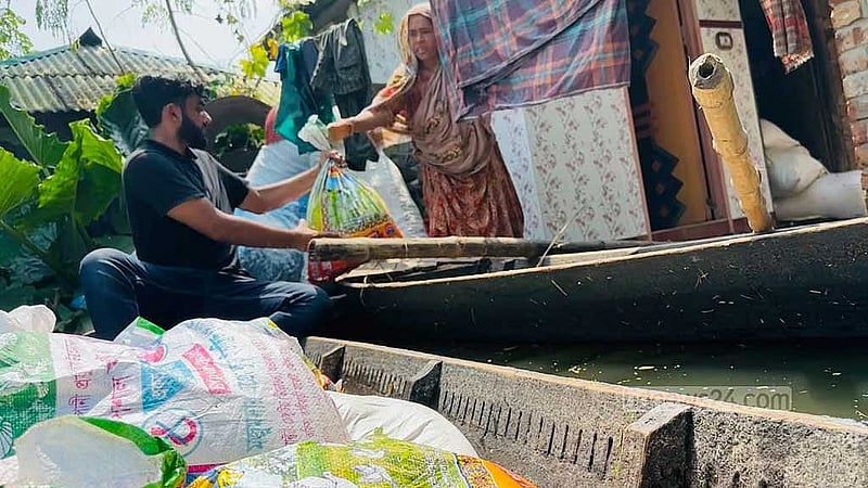 বাড়িতে পানি ওঠায় নৌকায় ঘর পেতেছেন এই নারীর পরিবার। পানি ভেঙে সেখানে কিছু খাদ্য সহায়তা নিয়ে হাজির হন ‘আমরা অভয়নগরবাসী’ ব্যানারে একদল তরুণ। 