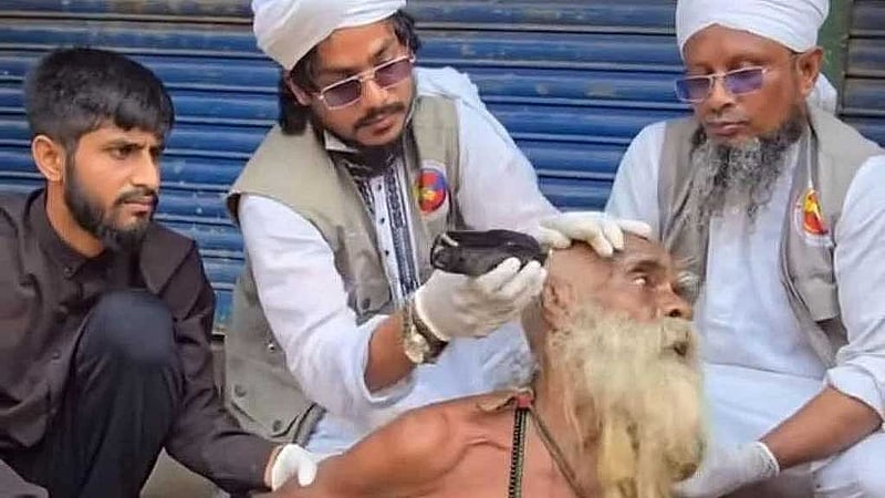 সম্প্রতি সামাজিক মাধ্যমে ছড়িয়ে পড়া ভিডিওটি থেকে নেওয়া ছবি। এখানে কয়েকজন মিলে প্রকাশ্যে একজন বৃদ্ধের চুল কেটে দিচ্ছেন। এই বৃদ্ধ কোনো ভবঘুরে নন, তিনি ওই এলাকারই বাসিন্দা এবং পরিবারের সদস্য।