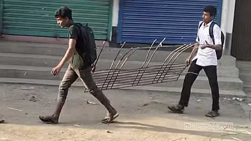 পলাশবাড়ী উপজেলা আওয়ামী লীগের কার্যালয়ে শনিবার ভাঙচুরের পর জানালার গ্রিল হাতে দুই কিশোর।