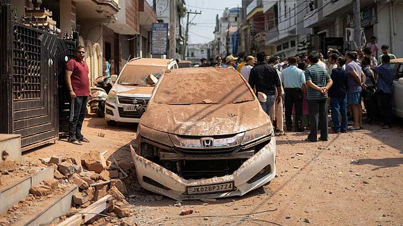জম্মু শহরে পাকিস্তানি বাহিনীর হামলায় ক্ষতিগ্রস্ত গাড়ির পাশে দাঁড়িয়ে আছেন স্থানীয় বাসিন্দারা। ছবি: রয়টার্স 