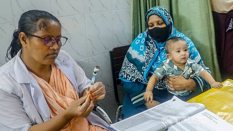 ঢাকার মুগদা নগর মাতৃসদন কেন্দ্রে একটি শিশুকে নিয়মিত টিকা কার্যক্রমের অংশ হিসেবে হামের টিকা দেওয়ার প্রস্তুতি নিচ্ছেন স্বাস্থ্যকর্মী