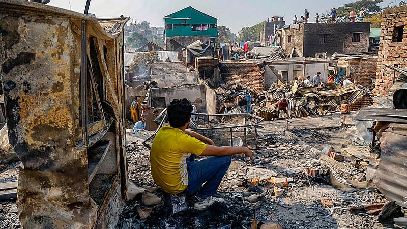কড়াইল বস্তির পুড়ে যাওয়া শোকেসের সামনে বসে আছেন এই তরুণ। যখন আগুন লাগে, তখন তিনি কাজে ছিলেন। খবর পেয়ে যখন ছুটে আসেন, তখন ঘরে ঢোকার মতন অবস্থা আর ছিল না