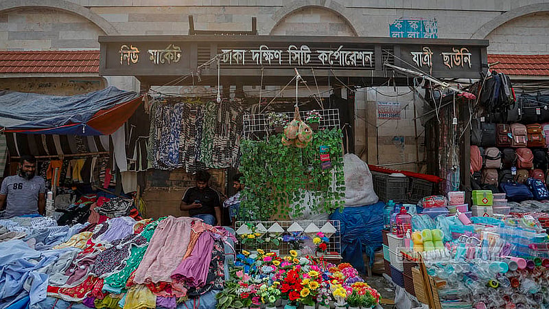 ঢাকার নিউ মার্কেটের ১ নম্বর গেইটের পাশে রয়েছে দক্ষিণ সিটি করপোরেশনের একটি যাত্রী ছাউনি; কিন্তু তা দেখে বোঝার উপায় নেই হকারদের উৎপাতে। ছবি: মাহমুদ জামান অভি