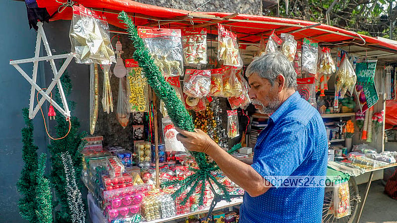 ক্রিসমাস ট্রি হাতে এক দোকানি। ঢাকার তেজগাঁও চার্চের সামনে একেকটি ক্রিসমাস ট্রি আকারভেদে বিক্রি হচ্ছে ২০০ টাকা থেকে ৪ হাজার টাকা পর্যন্ত