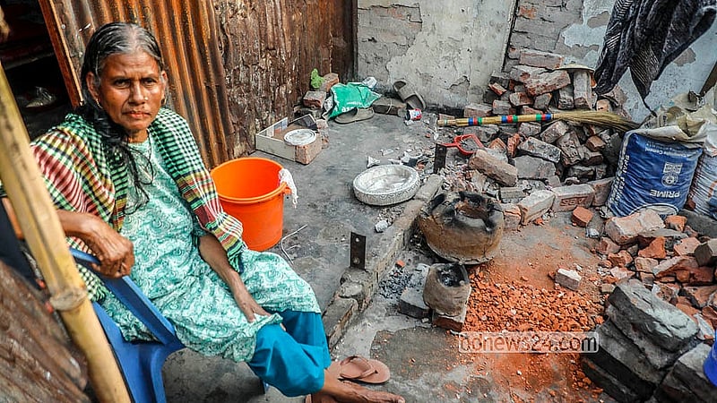 ঢাকার কড়াইল বস্তিতে আগুনে পুড়ে যাওয়া স্থানে বসে আছেন এক নারী