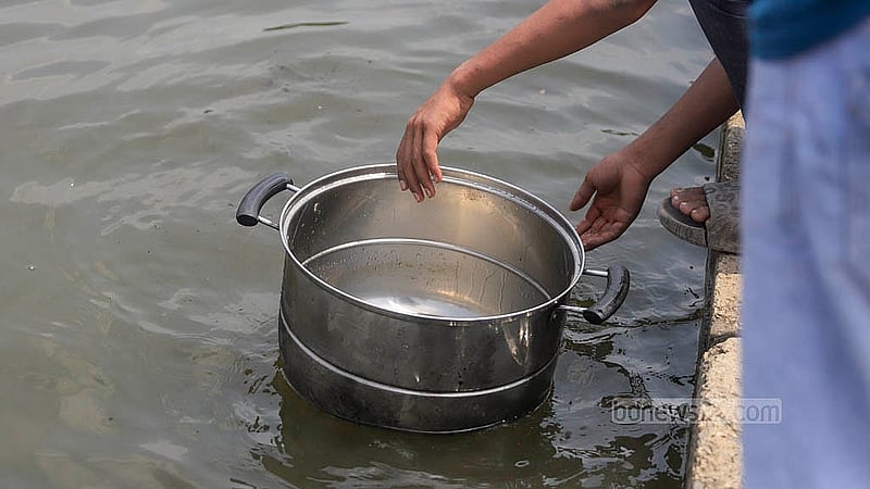 সোহরাওয়ার্দী উদ্যানের মোমো বিক্রেতা তার হাঁড়ি-পাতিল ধুয়ে নিচ্ছেন জলাশয়ের পানিতে। ছবি: আব্দুল্লাহ আল মমীন