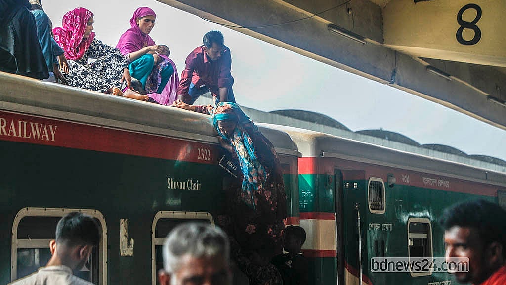 ঢাকায় কমলাপুর রেলওয়ে স্টেশনে শুক্রবার ট্রেনের ছাদ থেকে ঝুঁকি নিয়ে নামছেন যাত্রীরা।  ছবি: আব্দুল্লাহ আল মমীন