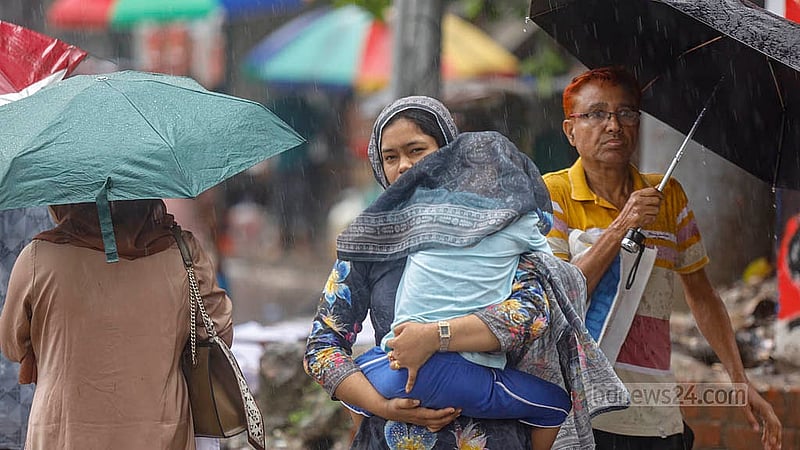 ঝুম বৃষ্টি; তার মধ্যে আবার শাহবাগ এলাকায় সড়ক অবরোধ। হাসপাতাল থেকে বেরিয়ে কোনো যানবাহন না পেয়ে ওড়না দিয়ে ঢেকে শিশুকে নিয়ে যাচ্ছেন এক নারী। ছবি: মাহমুদ জামান অভি