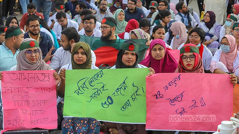 রাজধানীর শাহবাগ মোড় অবরোধ করে বিক্ষোভে প্ল্যাকার্ড হাতে ট্রেইনি চিকিৎসকরা। ছবি: আব্দুল্লাহ আল মমীন