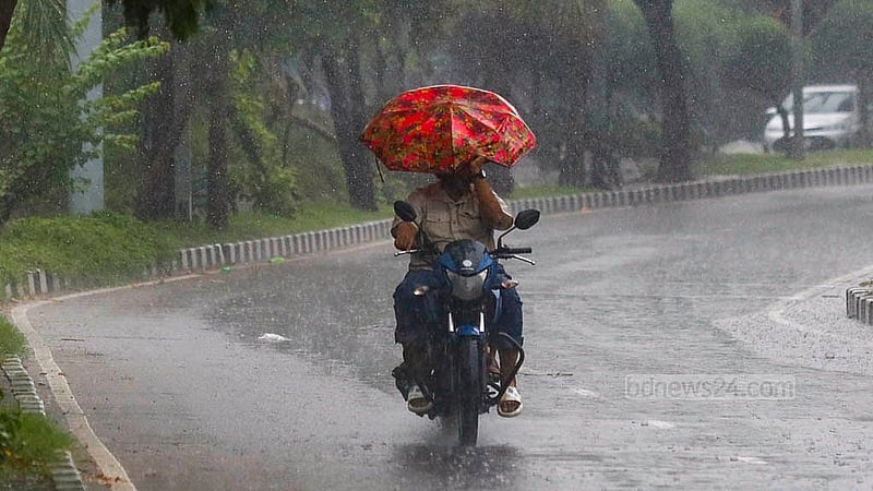 হাতিরঝিল এলাকায় বুধবার সকালের ঝুম বৃষ্টিতে মোটরসাইকেল চালাচ্ছেন চালক, পেছনে ছাতা মাথায় আরোহী। ছবি: মাহমুদ জামান অভি
