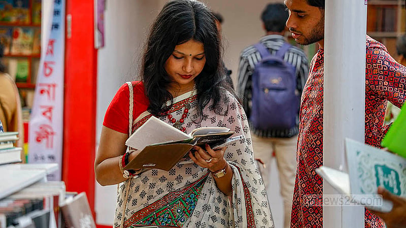 অমর একুশে বইমেলার একটি স্টলে শনিবার বই দেখছেন এক নারী। ছবি: মাহমুদ জামান অভি
