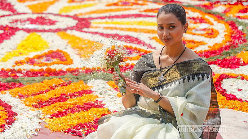 একুশে ফেব্রুয়ারিতে কেন্দ্রীয় শহীদ মিনার শ্রদ্ধার ফুলে ফুলে ভরে গেছে। সেখানেই বসে ছবি তুলছেন এক নারী। ছবি: আব্দুল্লাহ আল মমীন