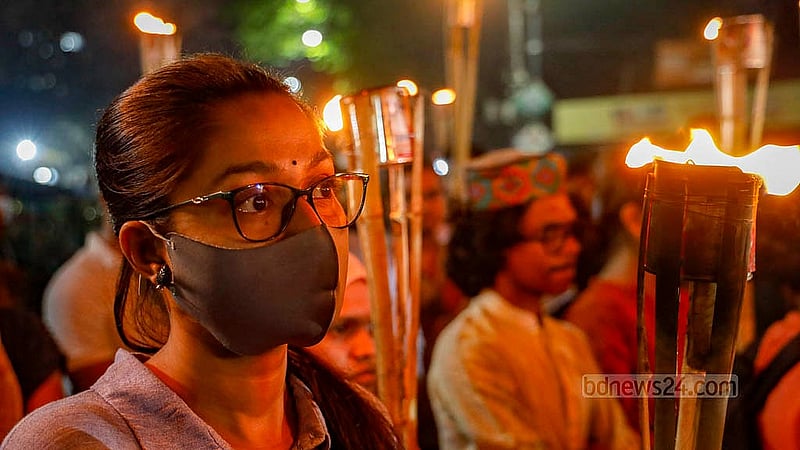 মশাল হাতে ধর্ষণ ও নারী নির্যাতনের প্রতিবাদে বৃহস্পতিবার রাতে ঢাকা বিশ্ববিদ্যালয়ের রাজু ভাস্কর্যের সামনে এক নারী। ছবি: মাহমুদ জামান অভি