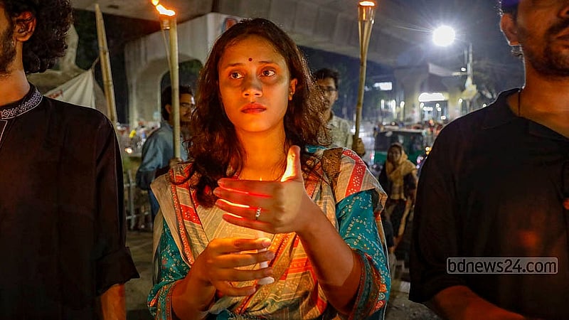 ধর্ষণ ও নারী নির্যাতনের প্রতিবাদে বৃহস্পতিবার রাতে রাজু ভাস্কর্যের সামনে মোমবাতি হাতে এক নারী। ছবি: মাহমুদ জামান অভি