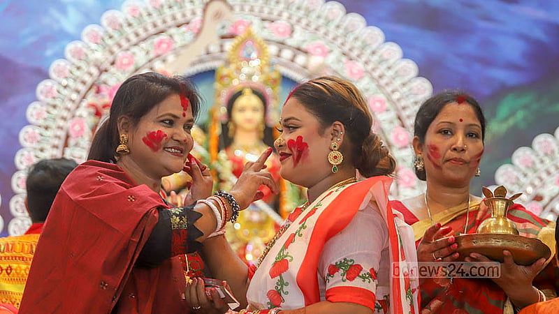 ঢাকেশ্বরী মন্দিরে রোববার বিজয়া দশমীতে দেবী বিদায়ের আগে দুর্গার চরণে দেওয়া সিঁদুর একজন পরিয়ে দেন আরেকজনের কপালে। ছবি: আব্দুল্লাহ আল মমীন