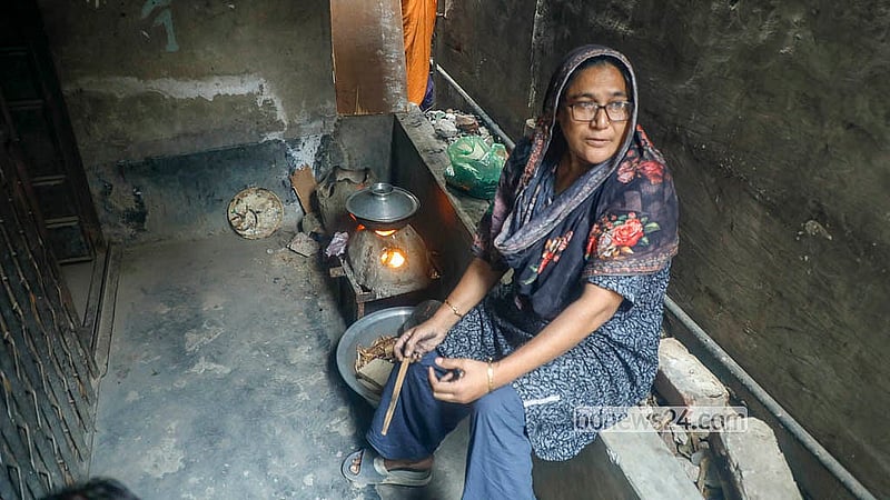 ঢাকার জুরাইন কমিশনার রোডের একটি বাড়ির ফটকের সামনে লাকড়ির চুলায় রান্না করছেন একজন