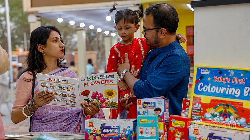 বইমেলার দ্বিতীয় দিন শুক্রবার সোহরাওয়ার্দী উদ্যানের একটি স্টলে বাবা-মায়ের সঙ্গে বই দেখছে এক শিশু