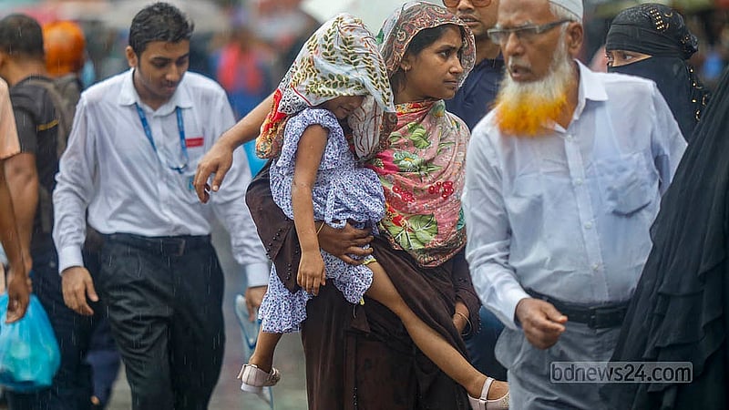 ঝুম বৃষ্টি; তার মধ্যে আবার শাহবাগ এলাকায় সড়ক অবরোধ। হাসপাতাল থেকে বেরিয়ে কোনো যানবাহন না পেয়ে ওড়না দিয়ে ঢেকে শিশুকে নিয়ে যাচ্ছেন এক নারী। ছবি: মাহমুদ জামান অভি
