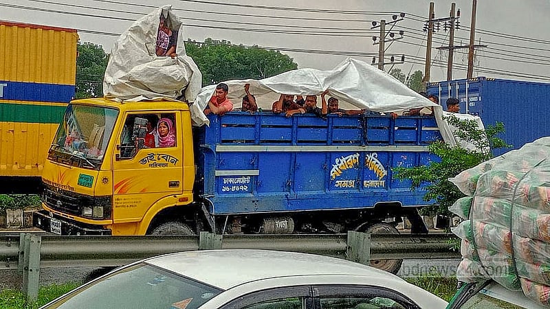 কোরবানির ঈদ উদযাপনে ঝুঁকি নিয়ে ট্রাকে করে বাড়ি ফিরছেন অনেকে। যমুনা সেতু সড়কে বৃহস্পতিবার দুপুরে বৃষ্টির মধ্যে তারা বিপাকে পড়েন। ছবি: মো. তোফাজ্জল হোসেন