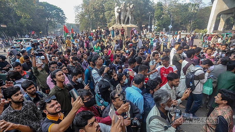 ঢাকা বিশ্ববিদ্যালয়ের রাজু ভাস্কর্য সংলগ্ন মেট্রোরেলের পিলারে সাবেক প্রধানমন্ত্রী শেখ হাসিনার প্রতিকৃতিতে জুতা নিক্ষেপ করা দেখে ভিড় করেন আশেপাশের মানুষ। ছবি: আব্দুল্লাহ আল মমীন