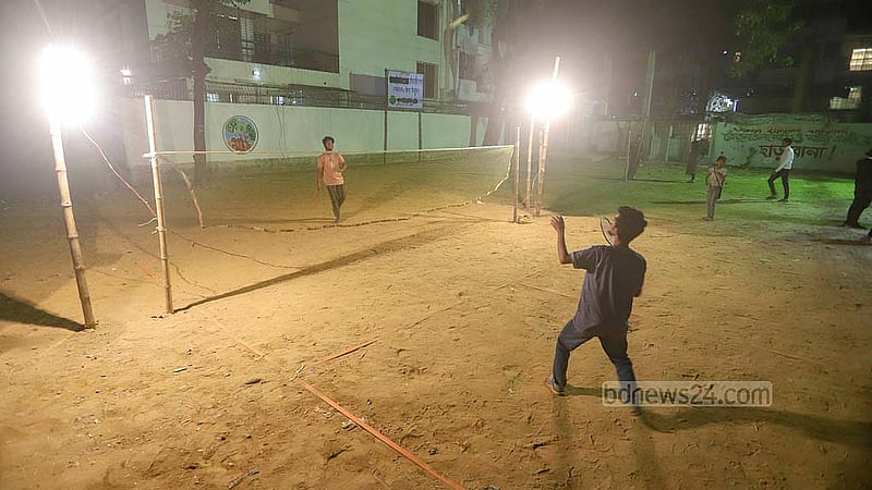 ঢাকার কলাবাগান তেঁতুলতলা মাঠে ফ্লাডলাইটের আলোয় চলছে ব্যাডমিন্টন খেলা। পাশে দাঁড়িয়ে উপভোগ করছেন অনেকেই। ছবি: আব্দুল্লাহ আল মমীন