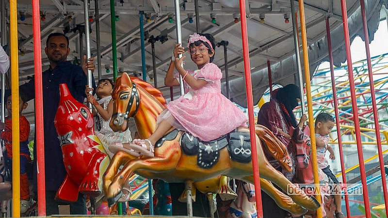 ঈদের দিন শনিবার শ্যামলীর শিশু মেলায় একটি রাইডে মা-বাবার সঙ্গে উচ্ছ্বসিত শিশুরা