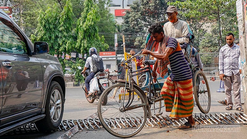 ঢাকার কাকরাইলে যাত্রী নিয়ে ট্র্যাপারের উপর দিয়ে রিকশা নিয়ে যাচ্ছেন এক চালক। কিছুটা ‘সমস্যা’ হলেও শেষ পর্যন্ত পার হয়ে যেতে পেরেছেন তিনি। ছবি: মাহমুদ জামান অভি