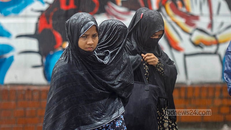 ঝুম বৃষ্টি; সঙ্গে আবার সড়ক অবরোধ। ফলে যানবাহন না পেয়ে কোনোমতে মাথায় কাপড় দিয়ে শিশুকে সুরক্ষা দেওয়ার চেষ্টা। বৃহস্পতিবার ঢাকার শাহবাগ থেকে তোলা। ছবি: মাহমুদ জামান অভি