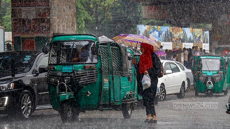 ঢাকার মগবাজার মোড়ে বুধবার দুপুরের বৃষ্টির মধ্যে ছাতা মাথায় রাস্তা পার হচ্ছেন এক নারী