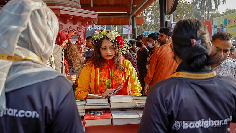 অমর একুশে বইমেলার একটি স্টলে শনিবার বই দেখছেন এক নারী। ছবি: মাহমুদ জামান অভি