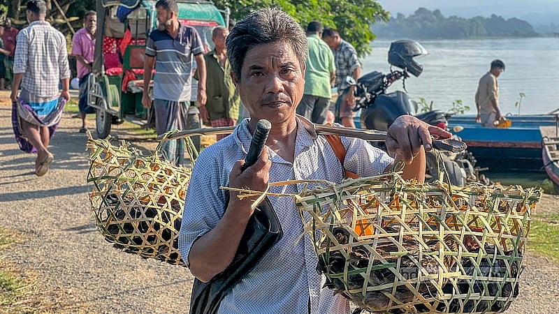 খাঁচায় মুরগি নিয়ে খাগড়াছড়ির মহালছড়ির হাটের পথে এক ব্যক্তি। ছবি: সমির মল্লিক