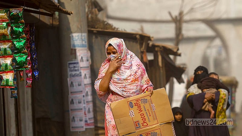 আশুলিয়া এলাকায় ধুলার কারণে মুখে হাত দিয়ে হেঁটে যাচ্ছেন এক নারী। ছবি: মাহমুদ জামান অভি