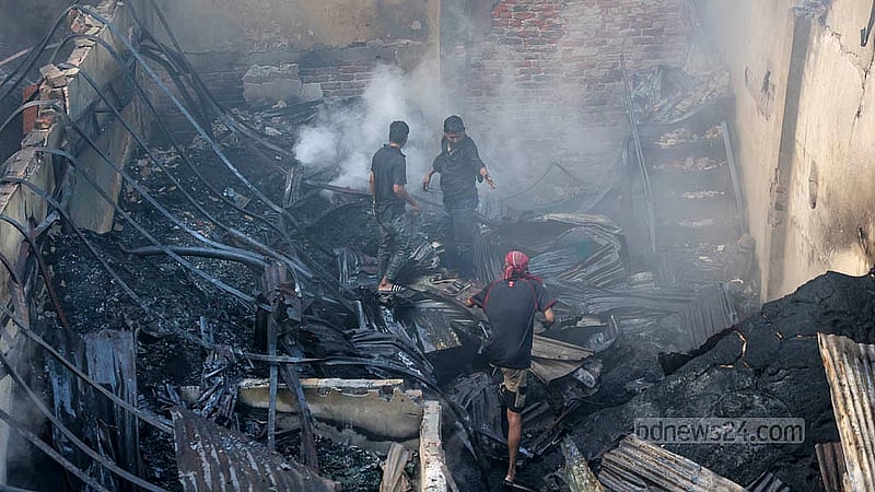 ইসলামবাগের চেয়ারম্যানঘাট এলাকায় প্লাস্টিকের গুদামের আগুন নিভেছে, কিন্তু ধোঁয়া উড়ছে। তার মধ্যে কিছু অক্ষত আছে কিনা, তা খুঁজে দেখছেন কয়েকজন।