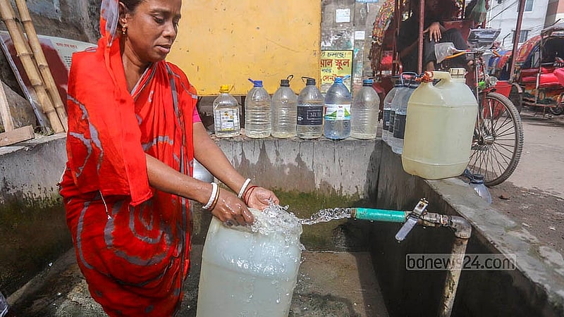 বাসাবাড়ির পানিতে দুর্গন্ধ থাকায় লালবাগের আমলিগোলা এলাকায় সড়কের পাশে ওয়াসার কল থেকে খাবার পানি সংগ্রহ করছেন এক নারী। ছবি: আব্দুল্লাহ আল মমীন