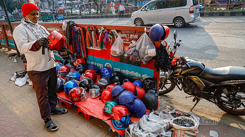 রাজধানীর সায়েন্সল্যাব মোড়ে ফুটপাতের দোকানে হেলমেট দেখছেন এক মোটারসাইকেল চালক। চলতি পথে ফুটপাথে হেলমেটের দোকান দেখে থেমেছেন তিনি