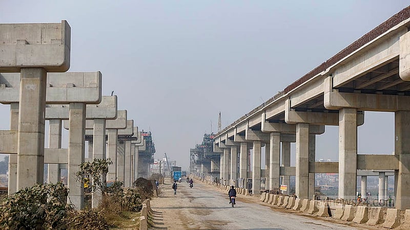 ঢাকা-আশুলিয়া মহাসড়কে একপাশে দাঁড়িয়ে আছে এলিভেটেড এক্সপ্রেসওয়ের পিলার, অপর পাশের পিলারগুলোতে বসে গেছে গার্ডার। ছবি: মাহমুদ জামান অভি