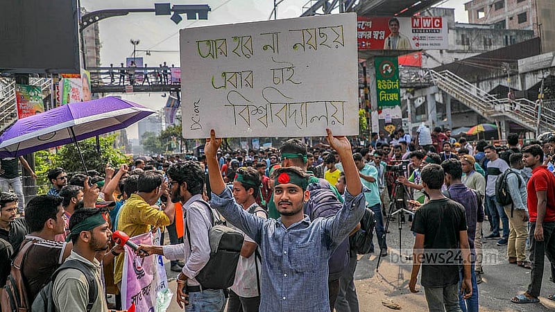 ঢাকা বিশ্ববিদ্যালয়ের অধিভুক্তি থেকে মুক্তি এবং স্বতন্ত্র বিশ্ববিদ্যালয়ে রূপান্তরের দাবিতে মঙ্গলবার প্ল্যাকার্ড হাতে এক শিক্ষার্থী। ছবি: মাহমুদ জামান অভি