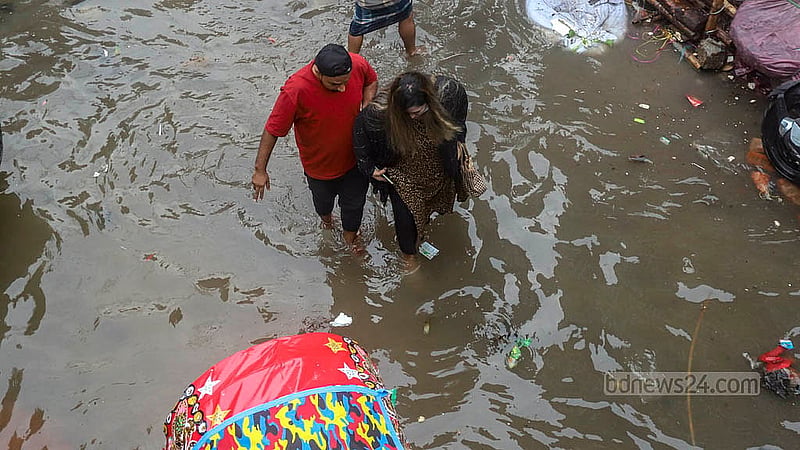 যাত্রাবাড়ীর শনির আখড়ায় খাল ও বৃষ্টির পানি একাকার। শনিবার ডুবে থাকা জিয়া সরণিতে ঝুঁকি নিয়ে চলাচল করে মানুষ ও যানবাহন।ছবি: আব্দুল্লাহ আল মমীন