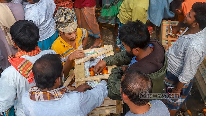 পুরান ঢাকার বাদমতলী ঘাটে ডাকে কেনা কমলার বাক্স খুলে দেখছেন এক ক্রেতা। ছবি: আব্দুল্লাহ আল মমীন