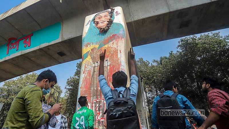 ঢাকা বিশ্ববিদ্যালয়ের রাজু ভাস্কর্য সংলগ্ন মেট্রোরেলের পিলারে শেখ হাসিনার গ্রাফিতিতে সোমবার ‘গণ জুতা নিক্ষেপ কর্মসূচি’ পালন করা হয়। ছবি: আব্দুল্লাহ আল মমীন